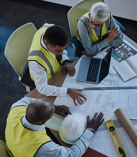 Construction workers reviewing blue print on table