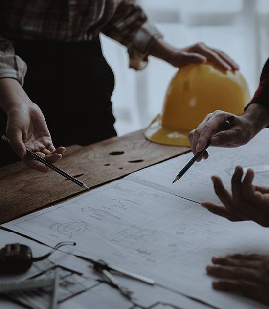 Construction working reviewing blue print on table